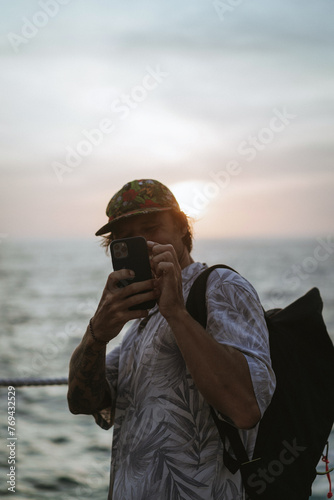 Man traveler with backpack in tourist place takes pictures on phone. photo