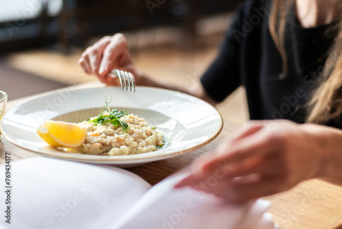 Mid-Section Of Woman Eating Rice And Reading A Book photo