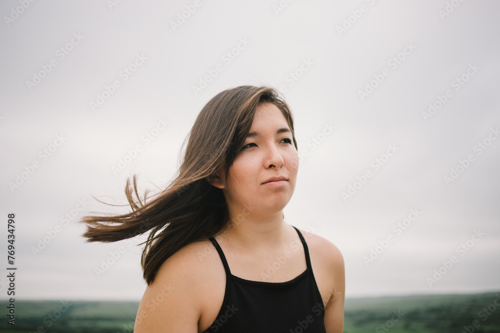 Half-Asian teenager looks off into distance while wind blows hair Half-Asian teenager looks off into distance while wind blows hair