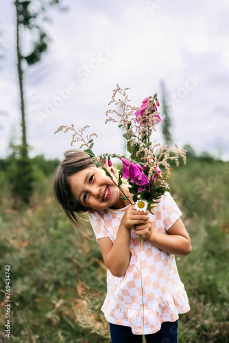 Asian girl smiling with flowers with the sun shining in field photo