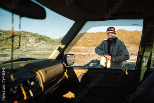 A young man stands in abstract light looking through a window. photo