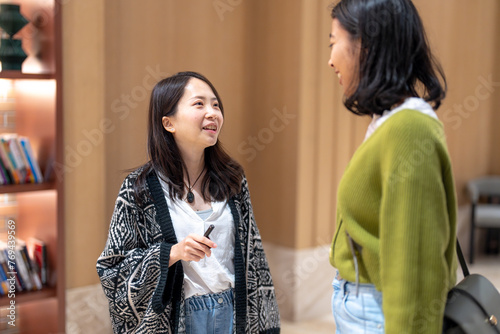 マンションのフロントロビーで３０代の台湾人女性と２０代のアジア人女性が談笑している風景 Scenery of Taiwanese women in their 30s and Asian women in their 20s chatting in the front lobby of the apartment