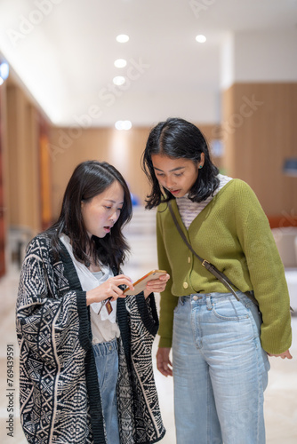 マンションのフロントロビーで３０代の台湾人女性と２０代のアジア人女性が談笑している風景 Scenery of Taiwanese women in their 30s and Asian women in their 20s chatting in the front lobby of the apartment