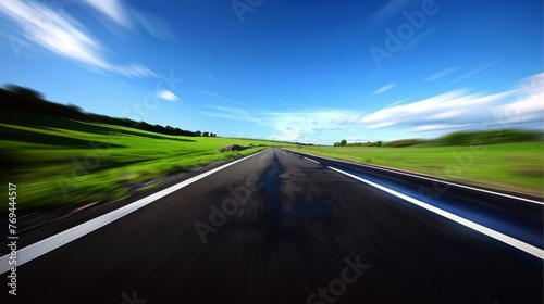 A blurry shot of a road with a blue sky in the background © hakule