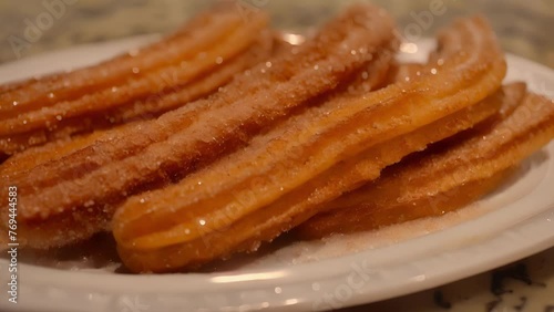 A white plate holding churros covered in sugar. photo
