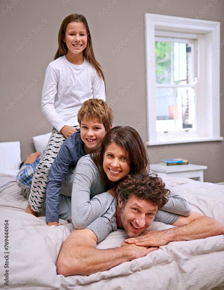 Fototapeta premium Stack, bed and family with portrait, children and relaxing with happiness and bonding together with fun. Home, mother and father with parents and kids with smile and bedroom with joy, play or morning
