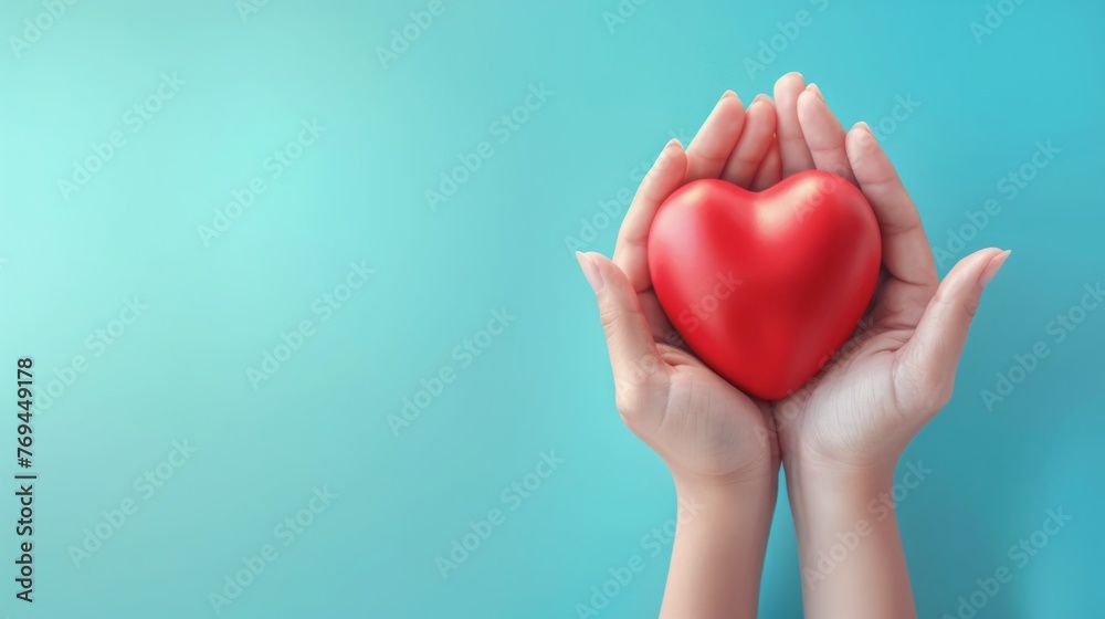 Young women hands holding red heart on blue background, health care, donate and family insurance concept, world heart day, world health day, CSR responsibility, adoption foster family Young women hands holding red heart on blue background, health care, donate and family insurance concept, world heart day, world health day, CSR responsibility, adoption foster family