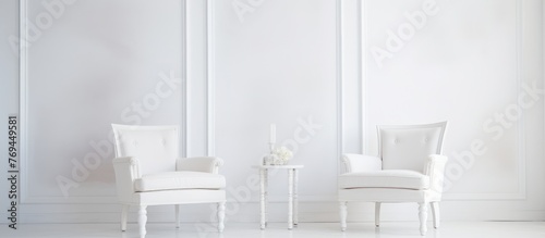 Two white chairs and a table made of wood in a white room with grey hardwood flooring, inside a building