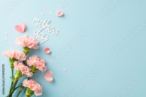 Stylish Mother's Day composition. Top view glance of newly-picked cloves, sweet message, diminutive hearts, and confetti on a pastel blue setting, space for text or publicity