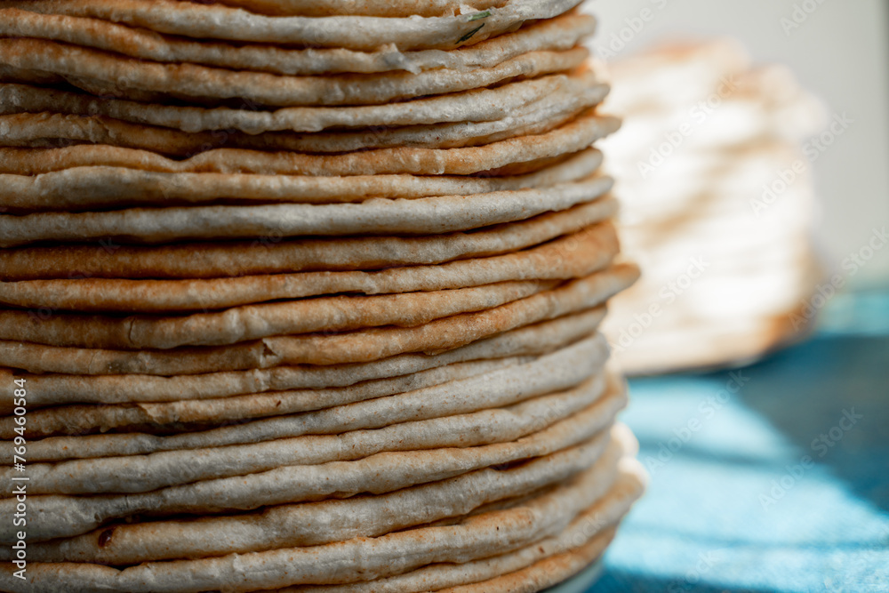 Flatbread lavash, chapati, naan, heap of tortilla on a blue background Homemade flatbread stacked. Flatbread lavash, chapati, naan, heap of tortilla on a blue background Homemade flatbread stacked.