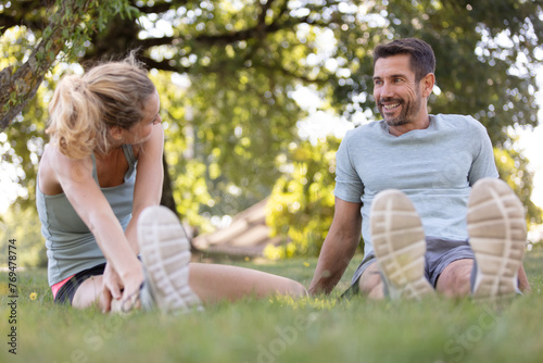 young couple exercising in park doing stretching