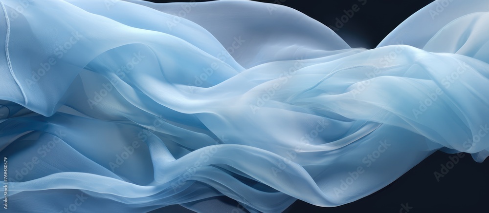 Obraz premium A close up of an electric blue silk cloth waving in the wind, resembling water waves in the sky against a black background