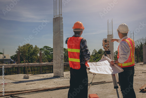 Engineer or surveyor worker working with theodolite transit equipment at outdoors construction site.