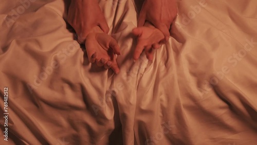 hands of girl woman and a man in hard sex and orgasm on a white sheet on the bed in close-up. Couple having sex
