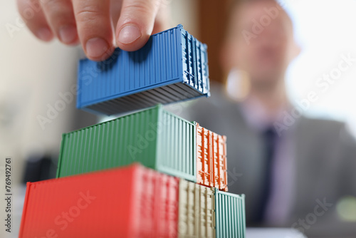 Business man arranging stack of freight containers on his table in office.