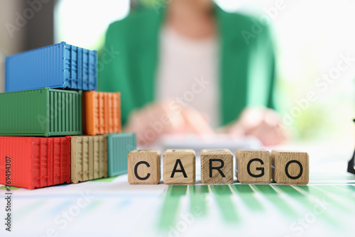 Word cargo and freight containers on financial reports on table, business woman in background.