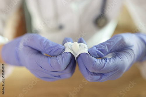Close-up of doctor's hands in gloves open suppositories for anal or vaginal use.