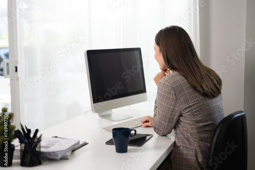 Side view of businesswoman watching online webinar on computer monitor at home office