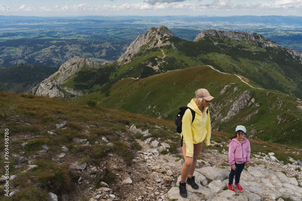 A mother and her little daughter are travelers high in the Polish Tatra Mountains near Mount Giewont on a summer day.