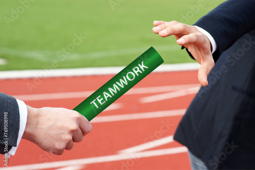 Businessman passes green teamwork baton to his teammate