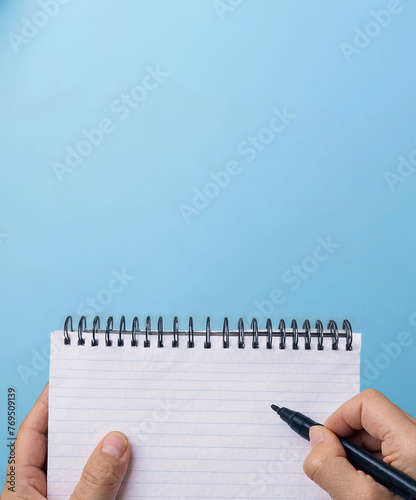 Hand writing on blank white notebook with blue background. Notepad mockup image.