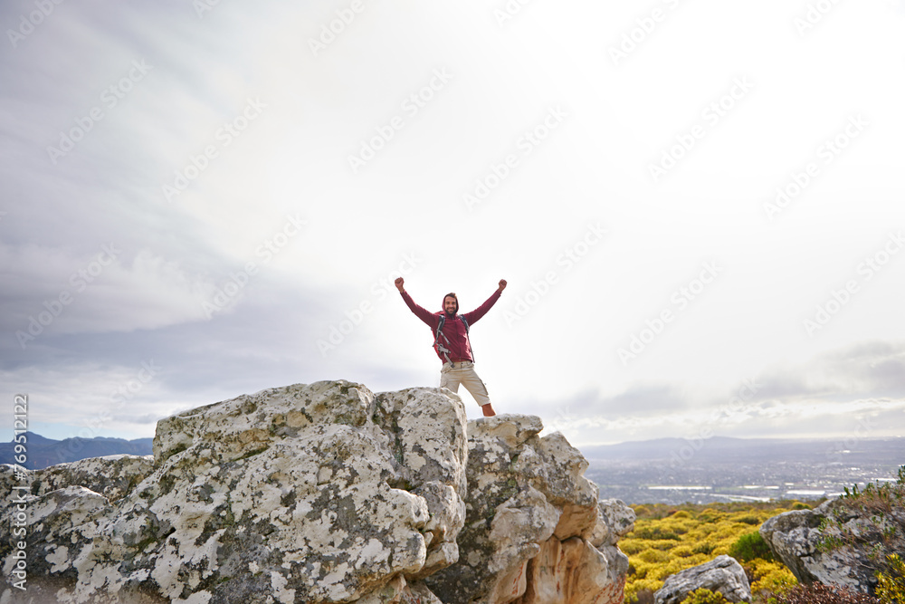 Motivation, success and man with winner on mountain, nature and rock for outdoor adventure. Male person, athlete and sport in environment for exercise, fitness and health with happiness by landscape