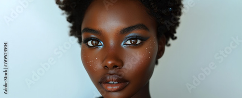 A woman with blue eyes and brown hair, whit blue eye shadow. She has a lot of glitter on her face. dark skinned woman, short hair, wearing make up, deep blue coloured eye shadow, length eye lashes