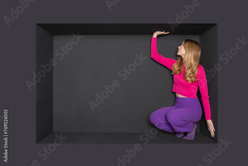 Blond teenager squatting in alcove over black background photo