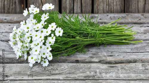 A bunch of white flowers are on a wooden table. The flowers are arranged in a way that they are all facing the same direction. The table is made of wood and has a natural, rustic feel to it