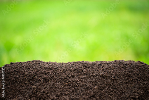 ground heap on a green background. black soil with blurred green grass