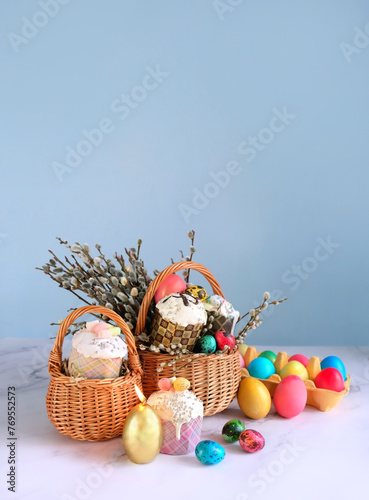 Easter holiday background. wicker basket with Easter cakes, colorful eggs and willow branches on table. Festive composition for Easter.