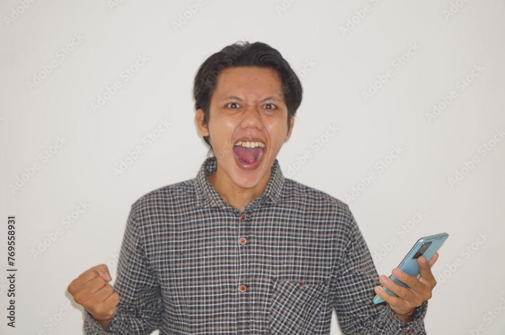 Asian young man wearing white shirt angry while holding smartphone isolated on white background - obrazy, fototapety, plakaty 