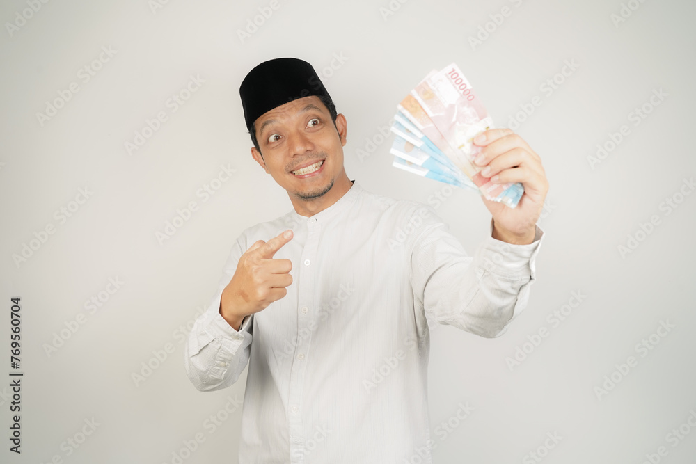 happy asian muslim man holding money, wearing arabic costume on isolated background - obrazy, fototapety, plakaty 