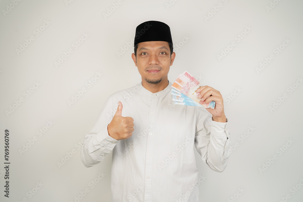 happy asian muslim man holding money, wearing arabic costume on isolated background - obrazy, fototapety, plakaty 