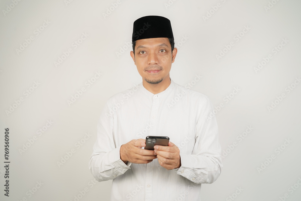 Asian Muslim man happy what he see in the smartphone on isolated background - obrazy, fototapety, plakaty 