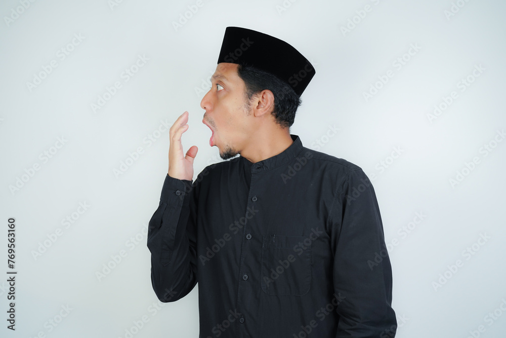 asian muslim man covering his mouth with hand or bad breath, wearing Arab turban sorban on isolated background - obrazy, fototapety, plakaty 