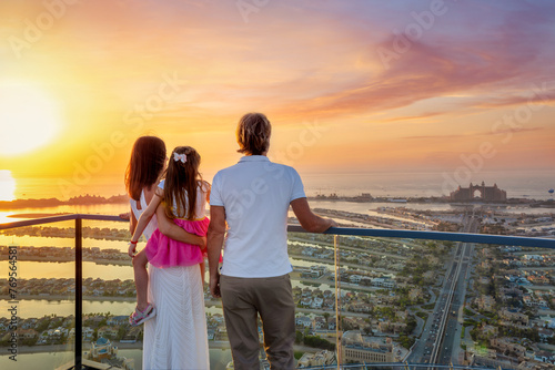 A family on holidays enjoys the beautiful view of The Palm island in Dubai, UAE, during a golden sunset