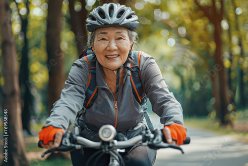 Happy asian senior woman in sportswear riding bicycle. She is leading an active lifestyle. Active old age concept
