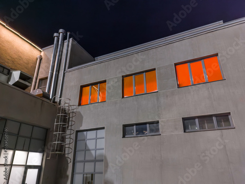 A building with orange windows and a white ladder. The building is tall and has a lot of windows