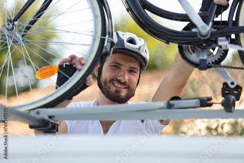 man taking his mountain bicycle from car roof