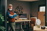 Portrait d'un homme debout souriant quinquagénaire senior hipster élégant et stylé dans un atelier créatif vintage