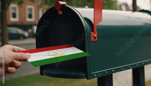Close-up of person putting on letters with flag Tajikistan in mailbox