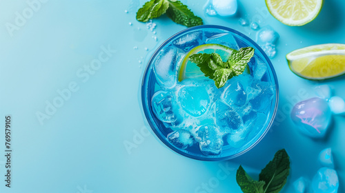 Vibrant flat lay of blue lagoon cocktail with fresh mint leaves, lime slices and ice cubes arround on pastel blue background. Minimal summer and party idea. Banner design, promotion, commercial photo