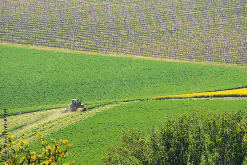 Tractor on a large green field with mowed lawn stripes. It is a sunny spring day in Czech Republic.