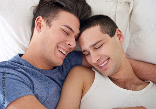 Men, gay and happy couple or bed embrace in apartment resting for lgbt pride with relax love, partner or connection. Male person, queer and smile with bonding support in home together, calm or peace © peopleimages.com