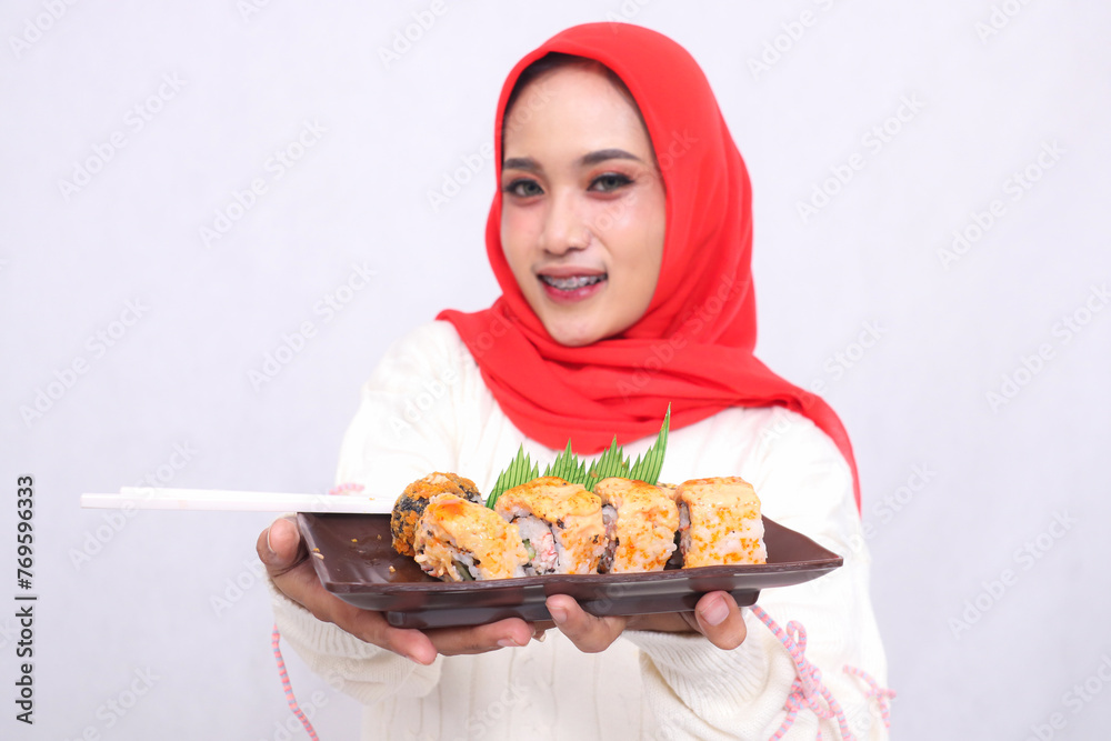 a plate containing a sushi dish (Japanese food) held by a beautiful indonesia woman while being happy for culinary, food and lifestyle content a plate containing a sushi dish (Japanese food) held by a beautiful indonesia woman while being happy for culinary, food and lifestyle content