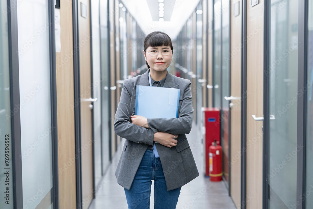 Professional woman holding folder in office corridor Professional woman holding folder in office corridor
