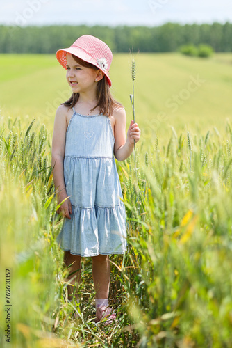 little girl in a dress and hat in the middle of a wheat field © Andrei