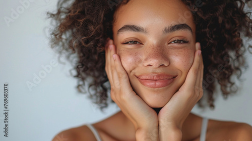 Portrait of a happy young woman holding her face with her hands, skincare