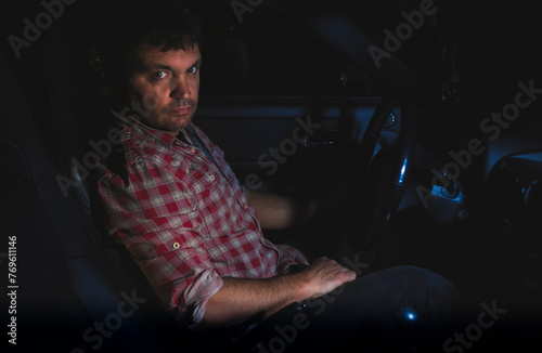 Homem sentado dentro do carro de noite